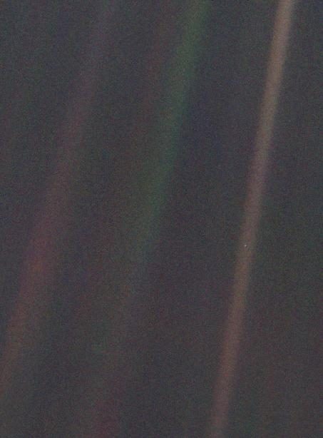 A grainy dark picture crossed by bands of colored light. One tiny pale dot sits inside the brownish band on the right.